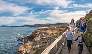 A family walk a boardwalk section of Bouddi coastal walk, Bouddi National Park. Photo: John Spencer/OEH.