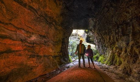 Two people walking through the Glow Worm Tunnel in Wollemi National Park. Photo: John Spencer &copy; DCCEEW