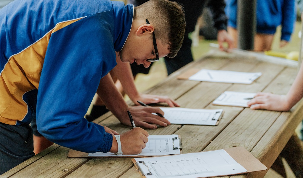 A student doing classroom based work, writing at a work table, Budderoo National Park. Credit: Remy Brand &copy; DCCEEW  