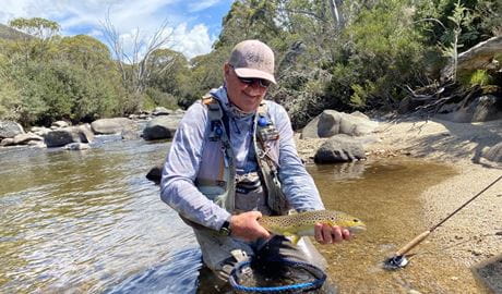 A man displaying his catch while fly fishing in Kosciuszko National Park. Photo &copy; Clearwater Fly Fishing Guides