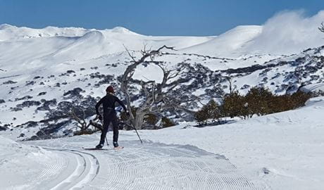 A skier skiing in Kosciuszko National Park with mountains in the distance. Photo: Jane Scheer &copy; K7 Ski School