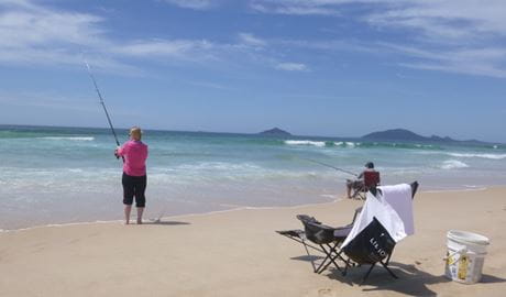 Two people fishing at the waters edge on a beach. Photo credit: Tony Neill &copy; Port Stephens Beach Fishing Safaris