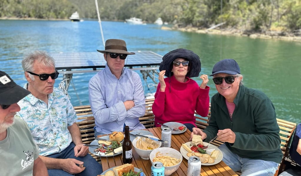 A group of people enjoying lunch on a private boat tour with Refuge Bay Charters in Ku-ring-gai Chase National Park. Photo: Nicholas Baillie Jackson &copy; Refuge Bay Charters