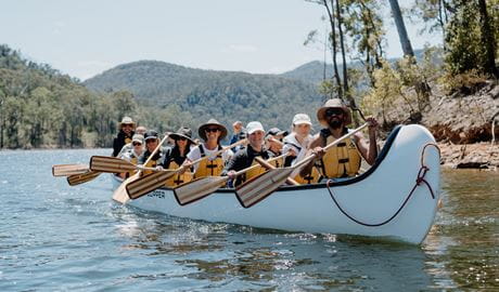 A group of people wearing yellow lifejackets paddling in a canoe. Photo: Lisa Grant &copy; Valley Outdoors