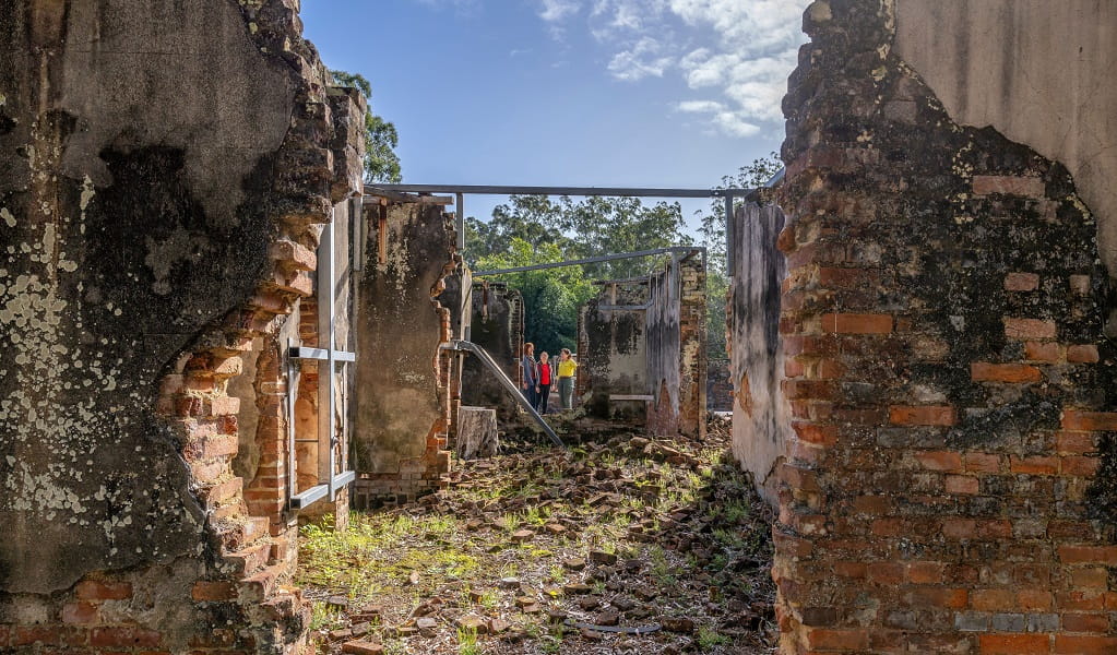 View of visitors through a collapsed brick wall in the ruins, Innes Ruins Historic Site. Image: John Spencer/DCCEEW