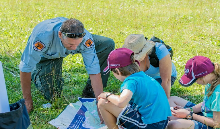 An NPWS ranger shows junior rangers how to read a map of a national park. Photo: John Spencer &copy; DPIE  