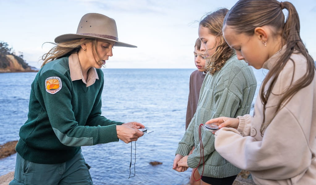 NPWS Ranger shows children a compass in Merimbula National Parkl. Photo: David Rogers &copy; DCCEEW