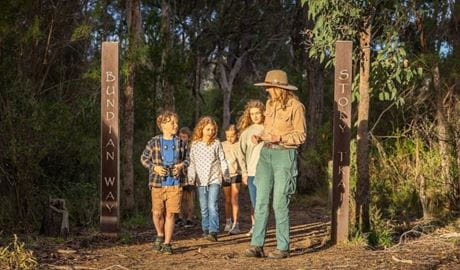 Group of children walking on path in bush with NPWS Ranger. Photo: David Rogers &copy; DCCEEW