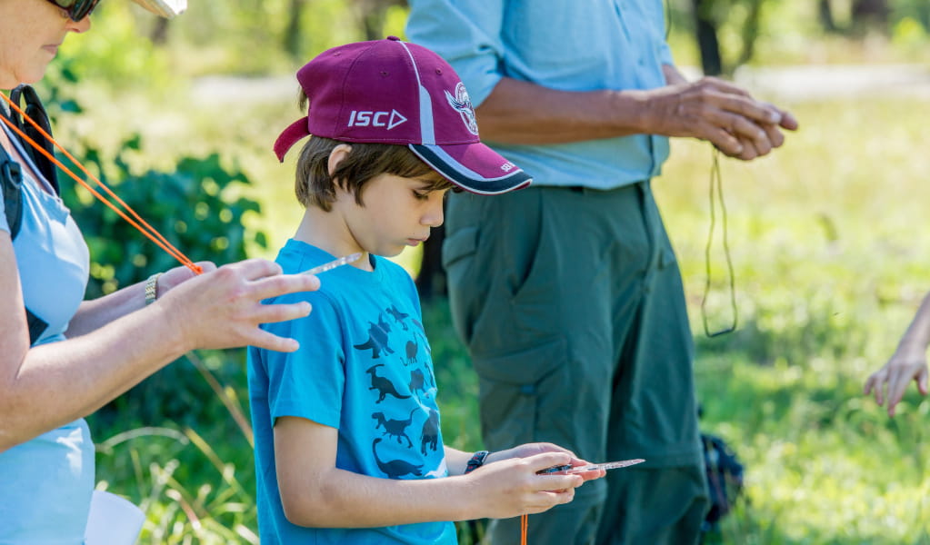 Young boy wearing hat looking at compass. Photo: John Spencer &copy; DCCEEW