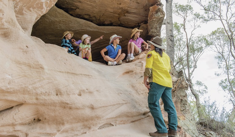 An NPWS guide talks to children at the Sandstone Caves, Pilliga National Park. Photo: John Spencer &copy; DPIE