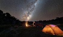 A tent, vehicle and campfire under the starry night sky. Photo: Ryan Heldoorn &copy; DCCEEW