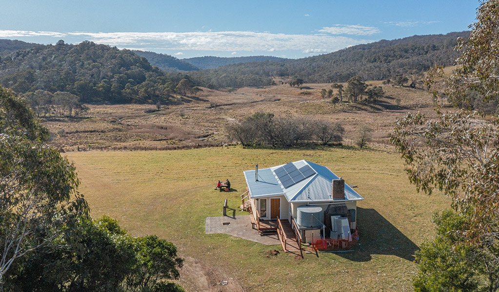 Newly upgraded Mooraback Cabin in Werrikimbe National Park, surrounded by expansive grassy lawn and rolling countryside hills. Credit: Josh Smith &copy; Josh Smith/DCCEEW