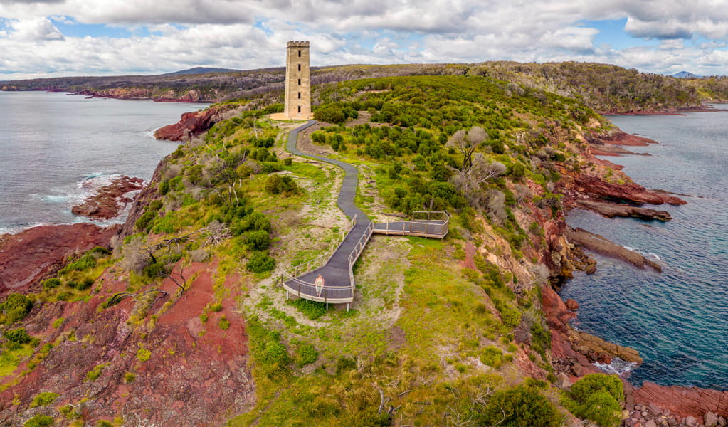 Boyds Tower with its surrounding red rock coastline, Beowa National Park near Eden. Photo: John Spencer, &copy; DCCEEW