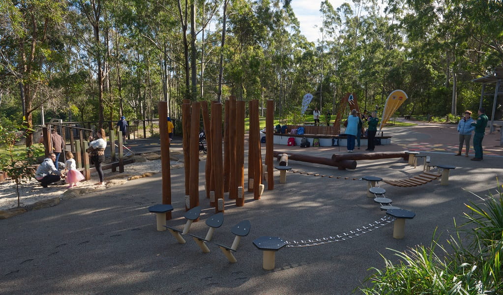 A wider view of the playground, with people and children playing, Village Green picnic area and playground, Blue Gum Hills Regional Park. Credit: Stuart Cohen, Bottle Brush Media © DCCEEW
