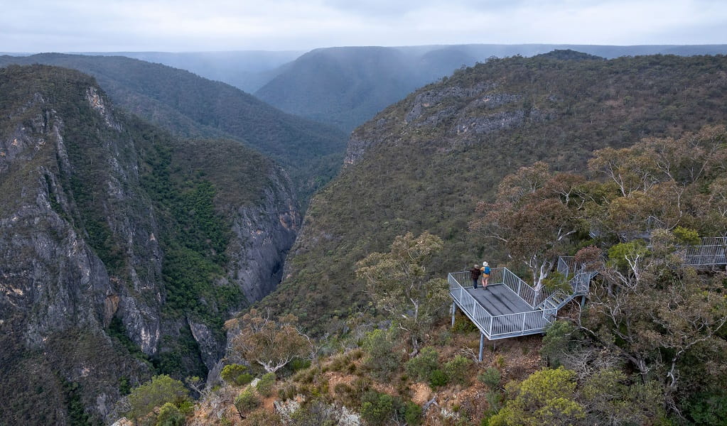 Aerial view of Adams lookout, with 2 people admiring the view over dramatic gorges, Bungonia National Park. Photo: John Spencer/DCCEEW