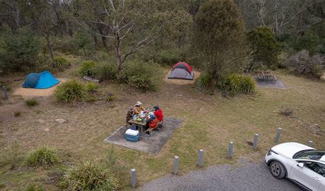 A group of campers eating at the picnic table next to their campsite at Bungonia campground. Photo: John Spencer/DCCEEW &copy; DCCEEW