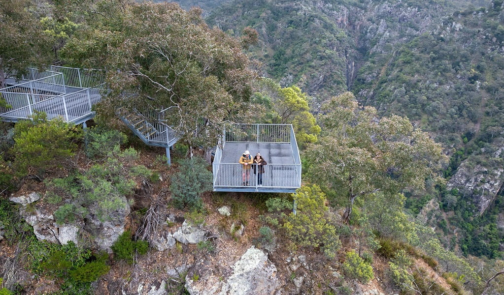 Two visitors look down into the bush and cliff face at Adams lookout and picnic area, Bungonia National Park. Photo: John Spencer &copy; DCCEEW 