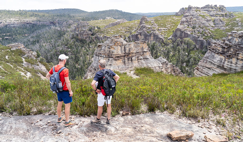 2 people looking out at the pagoda views of Lost City from the northern end of Lost City walking track in Gardens of Stone State Conservation Area. Credit: Simone Cottrell &copy; DCCEEW