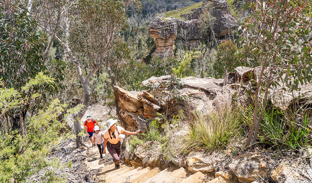 2 adults and a child walking up stone steps towards the northern end of Lost City walking track in Gardens of Stone State Conservation Area. Credit: Simone Cottrell &copy; DCCEEW