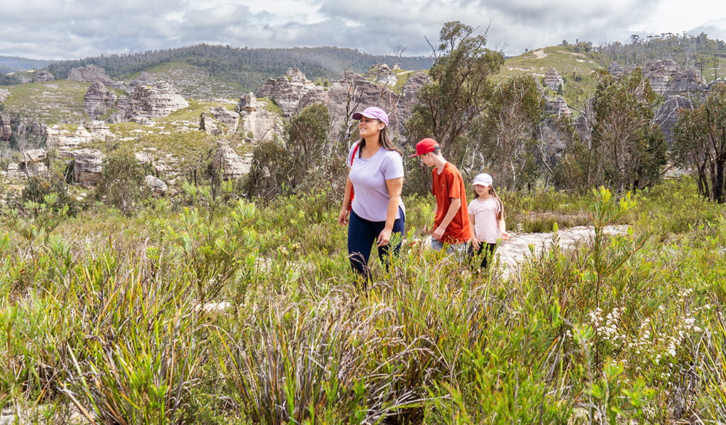 A woman and 2 kids hiking along Lost City walking track with pagodas in the background. Credit: Simone Cottrell &copy; DCCEEW