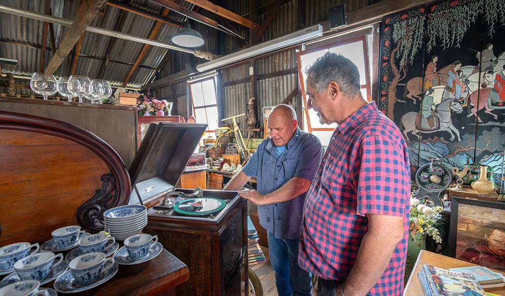 2 people looking at an antique record player inside the old Corneys Garage, now Gold Rush Antiques at Hartley Historic Site. Credit: John Spencer &copy; DCCEEW