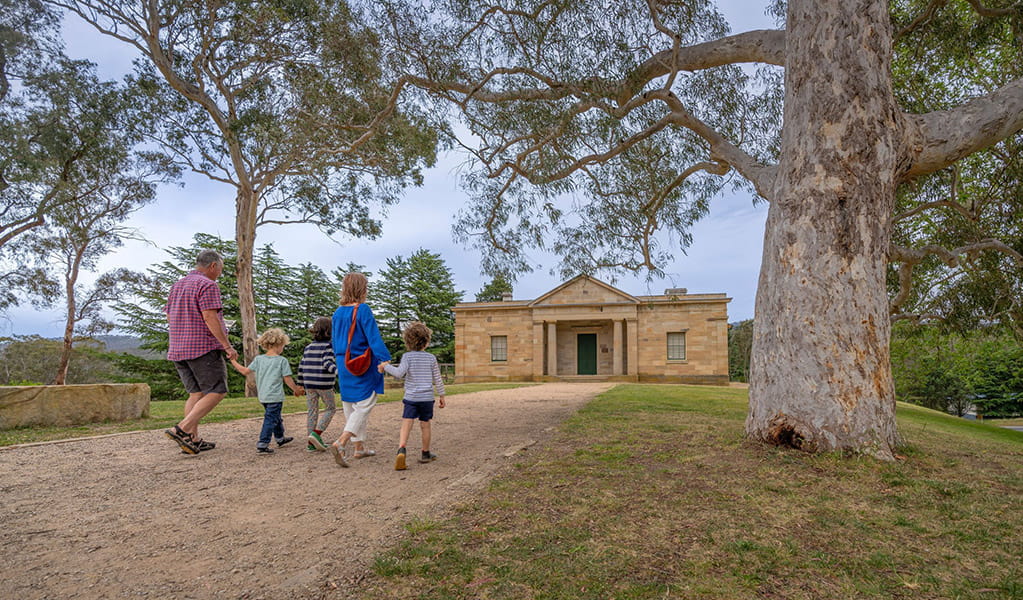 2 adults and 2 kids walking on a path towards Hartley Courthouse at Hartley Historic Site. Credit: John Spencer &copy; DCCEEW