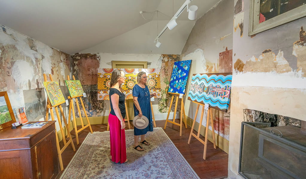 Visitors looking at Aboriginal paintings on display inside Hartley Historic Site Visitor Centre. Credit: John Spencer &copy; DCCEEW