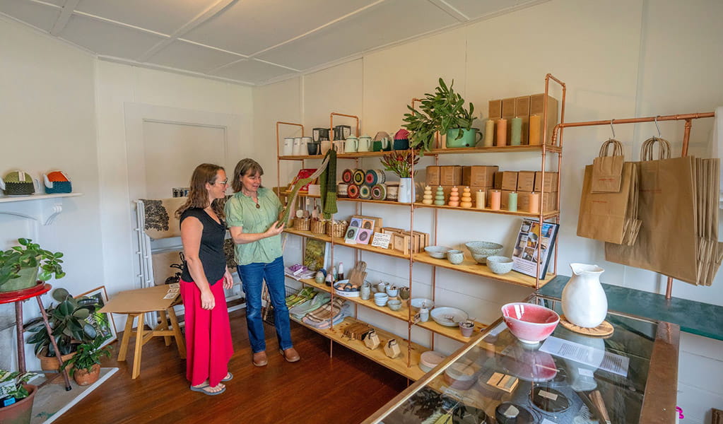 2 people browsing a selection of goods on display for sale at The Postmistress Cafe and Store at Hartley Historic Site. Credit: John Spencer &copy; DCCEEW