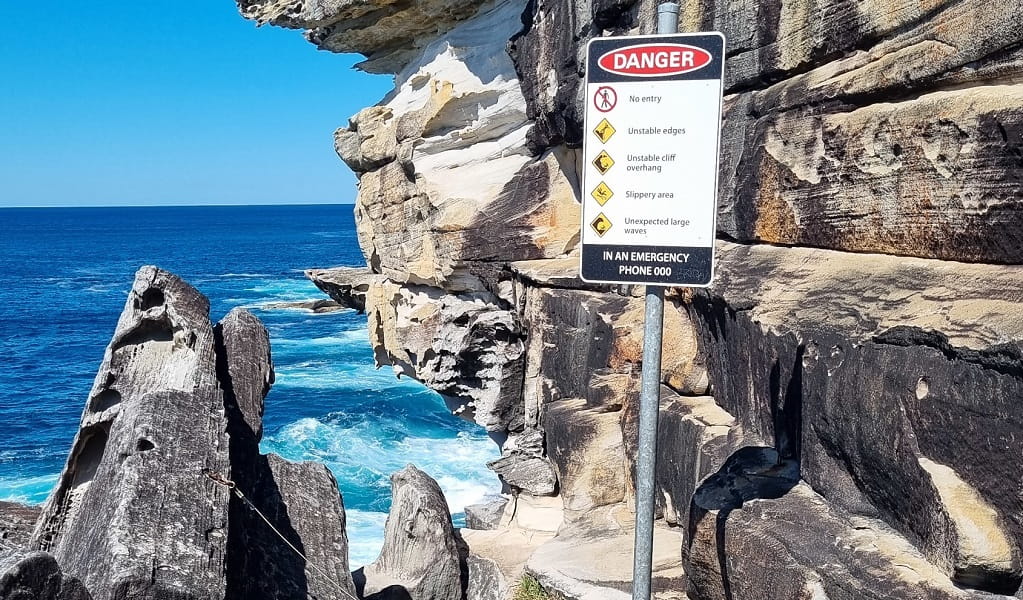 Sign warning of dangers of the cliff face and Skylight cave, Kurnell area, Kamay Botany Bay National Park. Photo: Jeremy Malgras &copy; DCCEEW