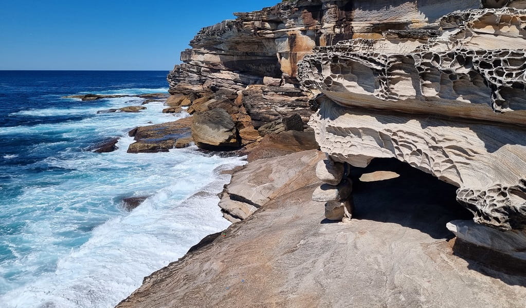 Skylight cave, which is an unstable and low rock overhang on a very narrow, sloping ledge, Kurnell area, Kamay Botany Bay National Park. Photo: Jeremy Malgras &copy; DCCEEW