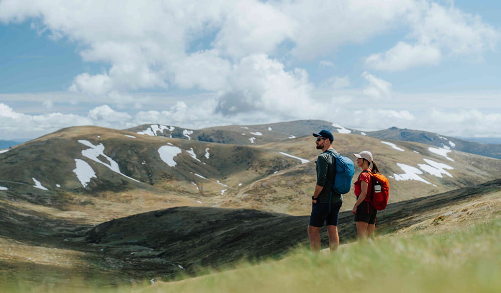 2 hikers admiring snow capped Main Range mountain views on day 2 of Snowies Alpine Walk. Credit: Remy Brand / DCCEEW &copy; Caravel Content