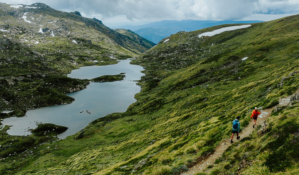 An aerial view of 2 hikers on Snowies Alpine Walk in the Thredbo-Perisher area with Blue Lake in the background. Credit: Daniel Parsons / DCCEEW &copy; Caravel Content