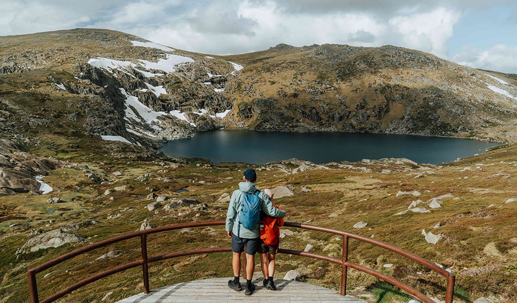 2 people admiring the view of Blue Lake in the Thredbo-Perisher area of Kosciuszko National Park. Credit: Remy Brand / DCCEEW &copy; Caravel Content