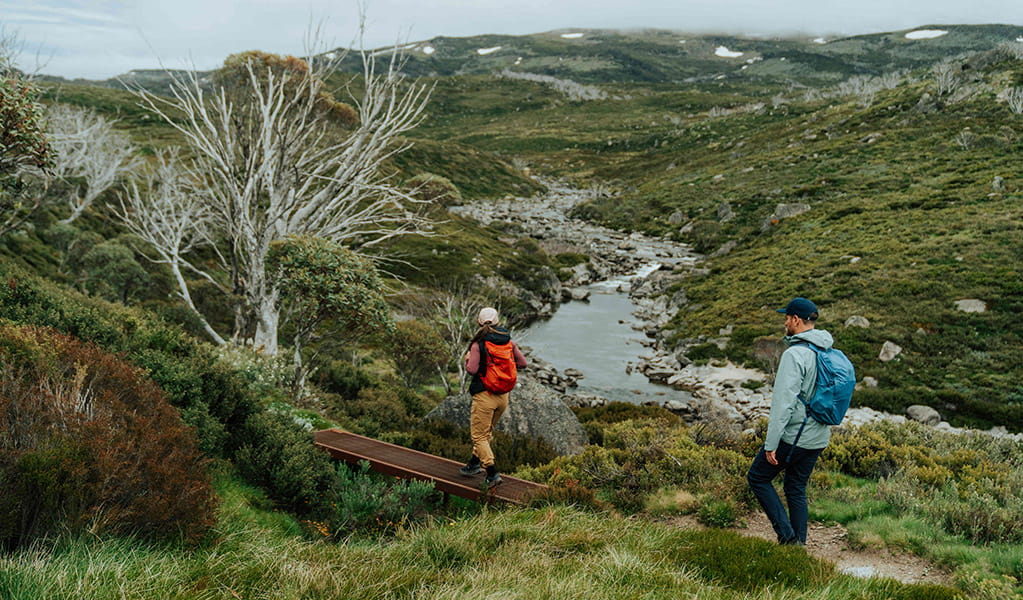 2 hikers crossing a small bridge over a creek on day 1 of Snowies Alpine Walk. Credit: Remy Brand / DCCEEW &copy; Caravel Content