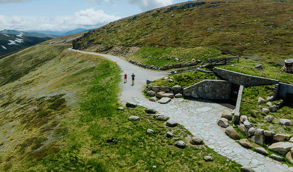 An aerial view of 2 people walking past facilities at Rawsons Pass along Main Range walk, Kosciuszko National Park. Credit: Daniel Parsons / DCCEEW &copy; Caravel Content