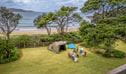 A family camping on a grassy site by the beach on the NSW north coast at Point Plomer campground in Limeburners Creek National Park. Credit: John Spencer &copy; DCCEEW