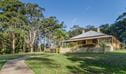 Roto House and the path leading up to it, surrounded by green lawn, gum trees and blue sky, Roto House Historic Site. Credit: John Spencer &copy; DCCEEW