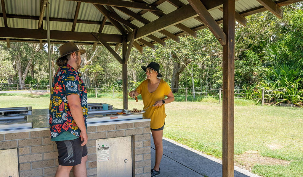 2 people cooking on a barbecue under a shelter at Mungo Brush campground, Myall Lakes National Park. Credit: John Spencer/DCCEEW &copy; DCCEEW