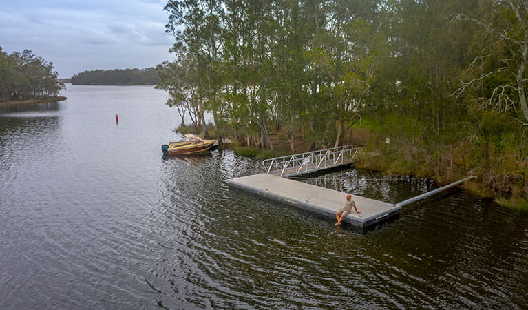 A man sitting on the wharf at Violet Hill campground in Myall Lakes National Park. Photo; John Spencer &copy; DPIE