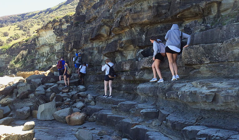People walking along steep rock face to Figure Eight Pools. Photo: Claire Competiello/OEH