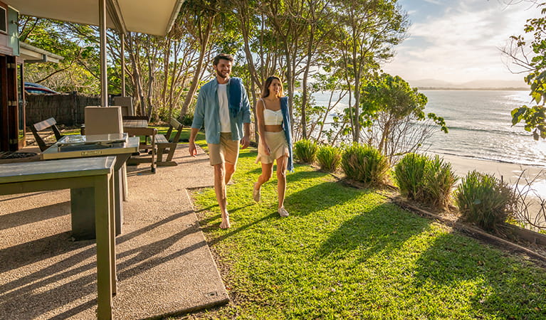 Couple walk through back garden by the beach at Mildenhall cottage. Photo: DPIE/John Spencer