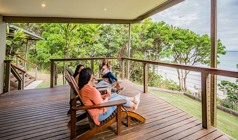 3 friends having a drink on the balcony at Thomson Cottage. Photo: Sera Wright/DPIE