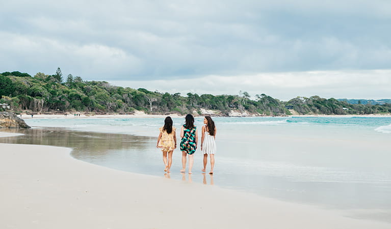 3 friends walking on The Pass beach in Walgun Cape Byron State Conservation Area. Photo: Sera Wright/DPIE