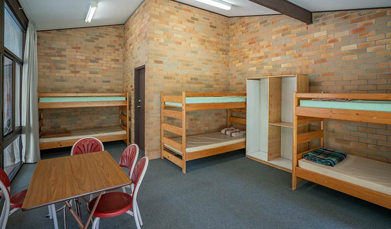 Three bunks beds and a communal table in one of the rooms in Wombeyan Caves dormitories. Photo: OEH/John Spencer
