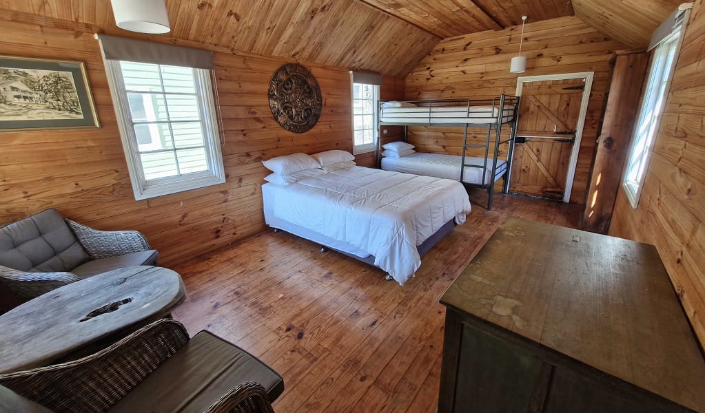 Inside The Tailors Room, Yerranderie Regional Park. The small cabin is completely built from wood, and has a double bed, bunk beds, a cabinet, chairs and table. Photo: Hassan Elbatoory &copy;DCCEEW