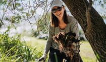 A volunteer with weeds she's removed, helping to restore native wildlife habitat. Credit: Remy Brand/DCCEEW &copy; the photographer